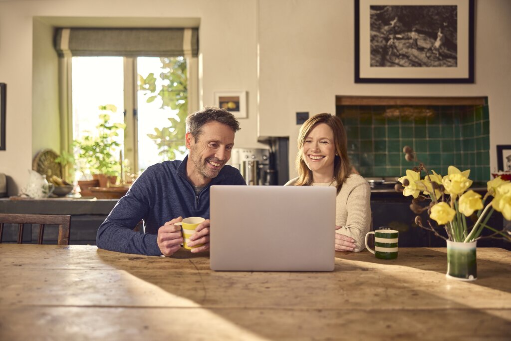 Couple video calling in the kitchen on a laptop.
