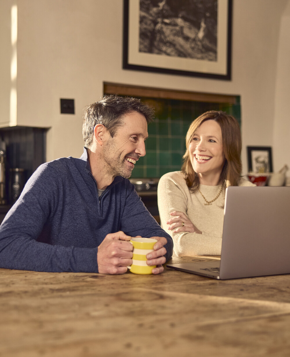 Happy couple smiling at the laptop with streaming internet