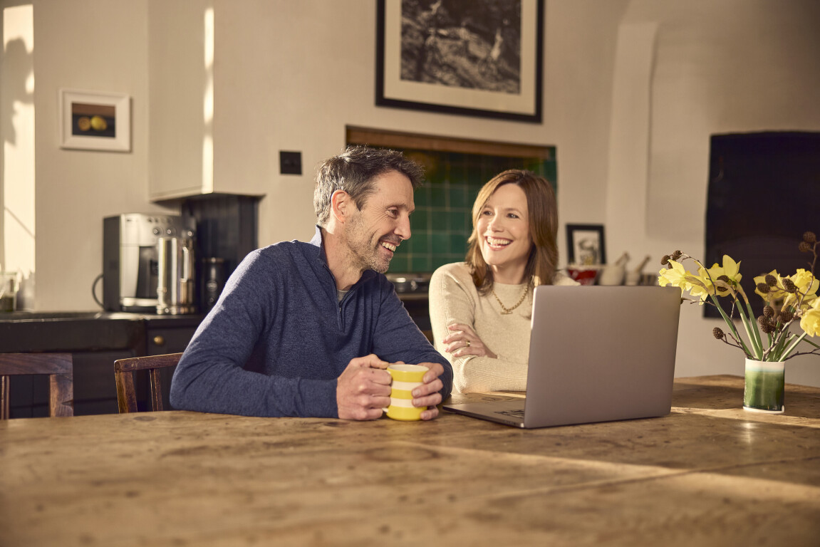 Happy couple smiling at the laptop with streaming internet